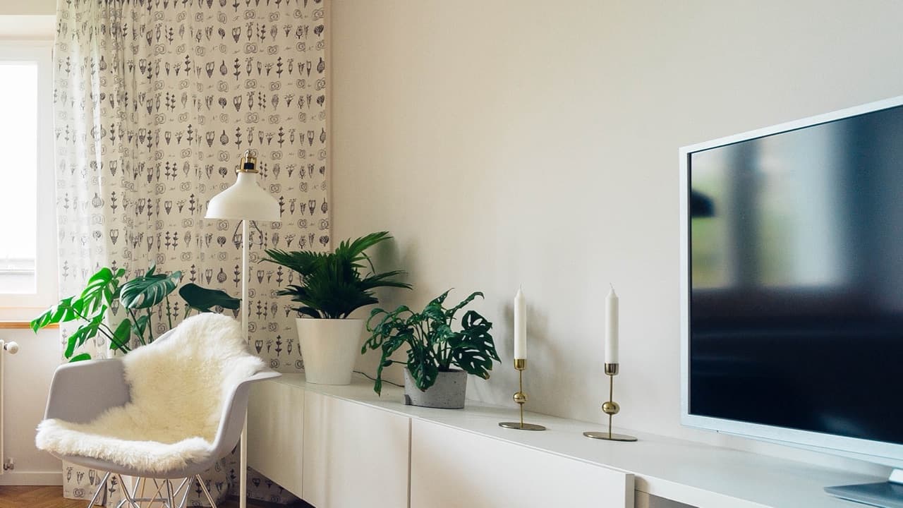 A flat-screen TV on a white media unit in a bright living room