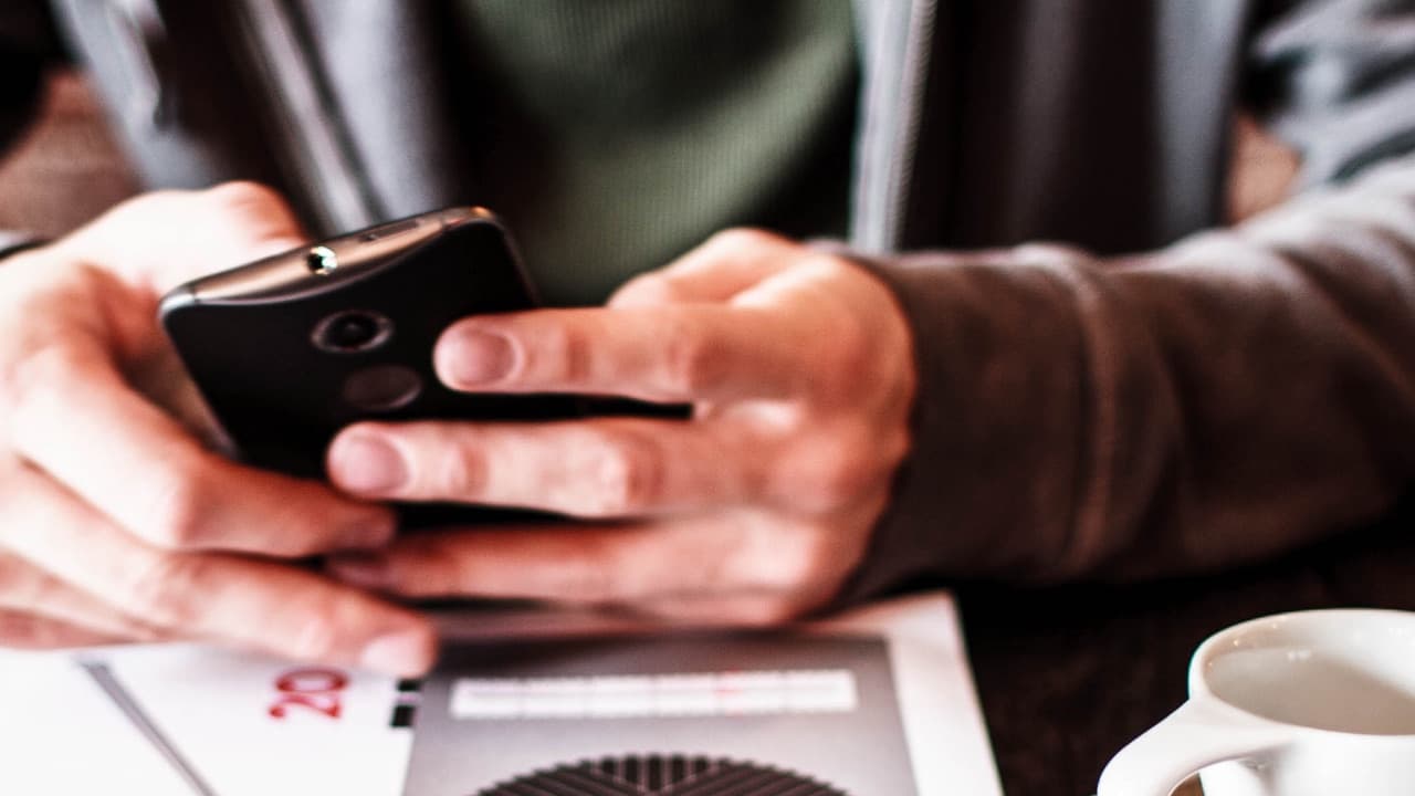 Hands holding a smartphone at a café table